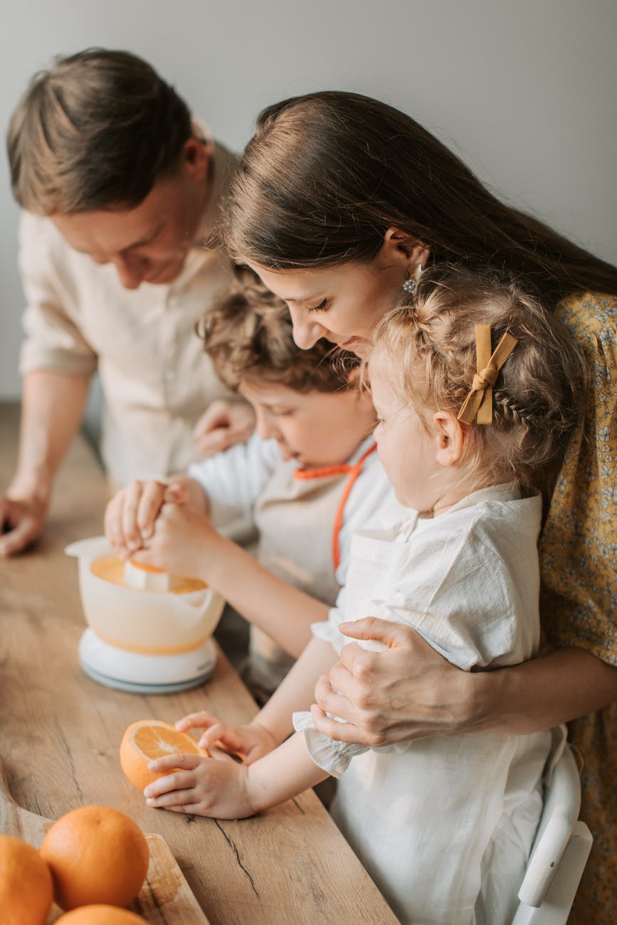 parents and children squeezing oranges